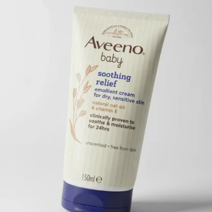 A tube of Aveeno Baby Soothing Relief Emollient Cream with a light blue cap, designed for dry, sensitive skin. The packaging features the Aveeno logo and text describing the cream's benefits, which include 24-hour moisturization and soothing properties with natural colloidal oatmeal.