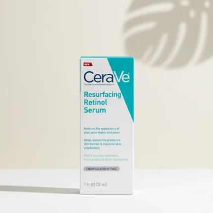 A professional, high-quality product photo of the CeraVe Resurfacing Retinol Serum box standing upright on a clean, light-colored surface with a soft, minimalist background and a subtle shadow of a leaf.